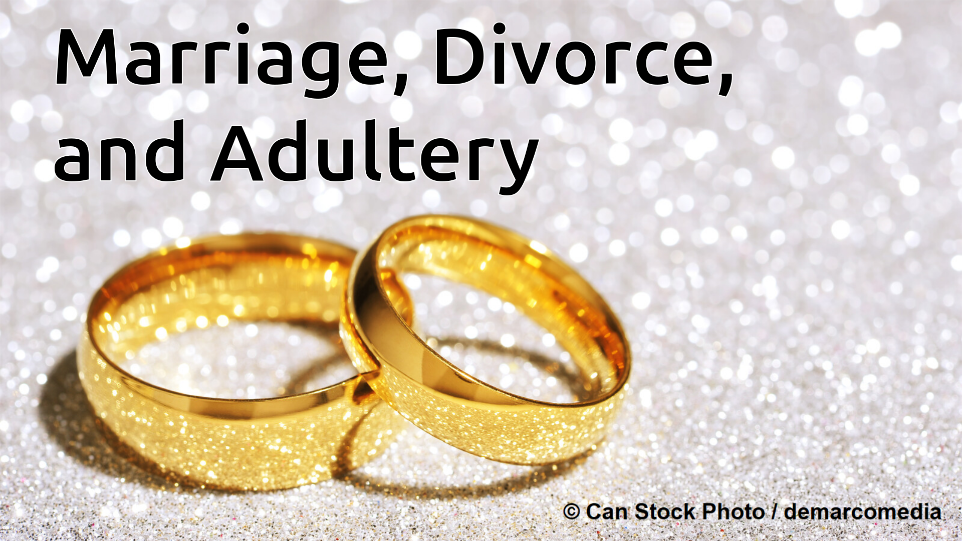 A picture of one gold wedding ring leaning on another on a sparkly surface.